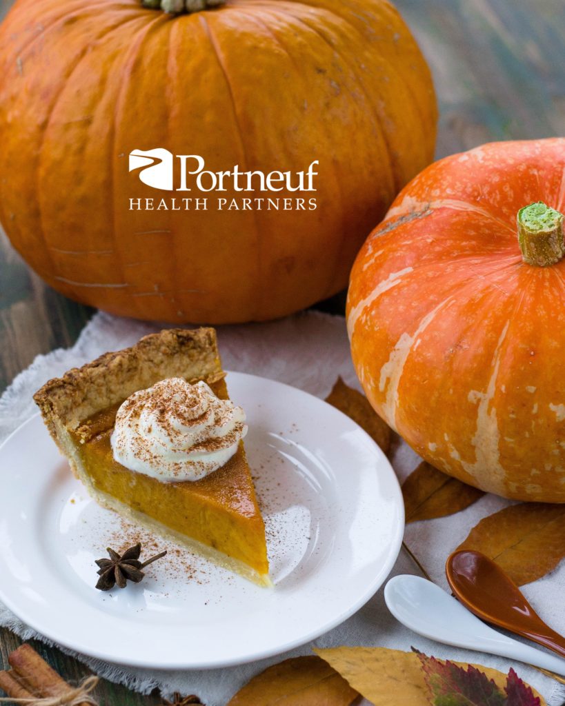 pumpkin pie on a white plate with two orange pumpkins as decorations